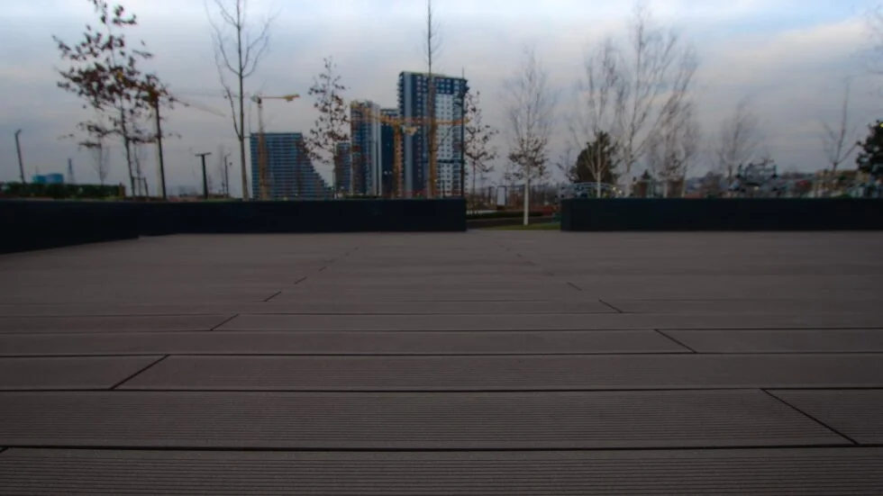Suprafață mare de decking WPC în aer liber, cu clădiri în construcție în fundal